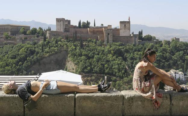 Unos turistas descansan y toman el sol en Granada. /Miguel Ángel Molina (Efe)