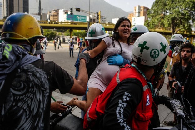 Personal médico auxilia a una joven embarazada afectada por los gases lacrimógenos durante una protesta en Caracas. :: C. Hernández / EFE