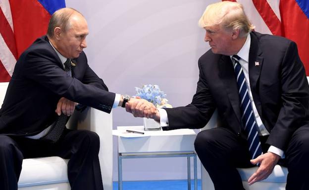 Putin (i) y Trump se dan la mano.
