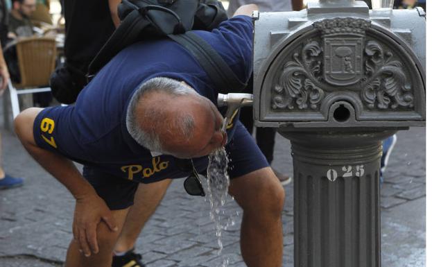 Un hombre bebe agua de una fuente en Madrid.