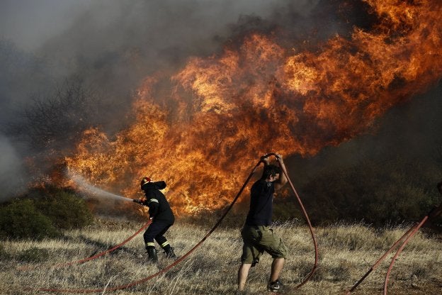 Un bombero y un voluntario luchan contra el fuego. :: efe
