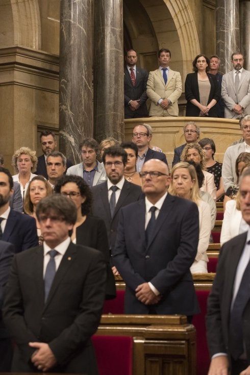 Puigdemont y Colau (al fondo) durante el minuto de silencio en el Parlamento catalán. :: M. Pérez / Efe