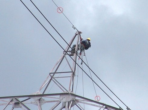 Un operario instala 'salvapájaros' en una torre de alta tensión.