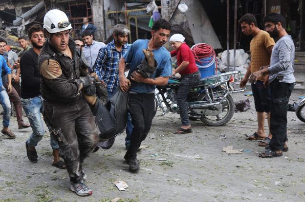 Seis miembros de la Defensa Civil siria trasladan a una víctima tras un ataque aéreo en un mercado de Idlib. :: M. Al-Bakour / Afp/