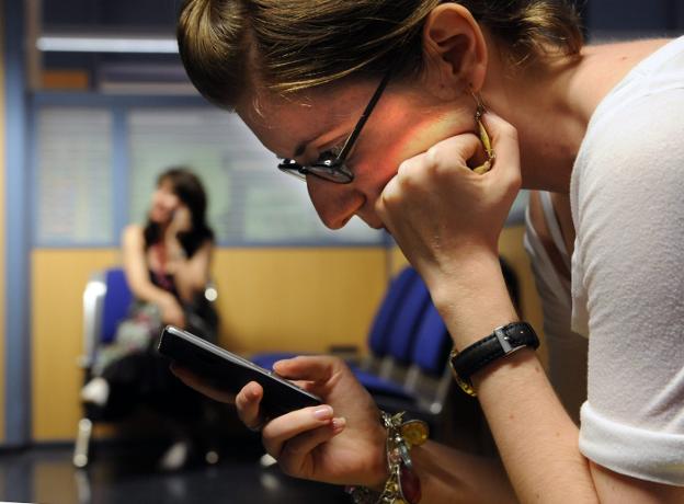 Una joven comprueba los mensajes en su teléfono móvil. :: r. c./