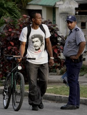 Un habanero pasa con su bici ante un policía. / AP/