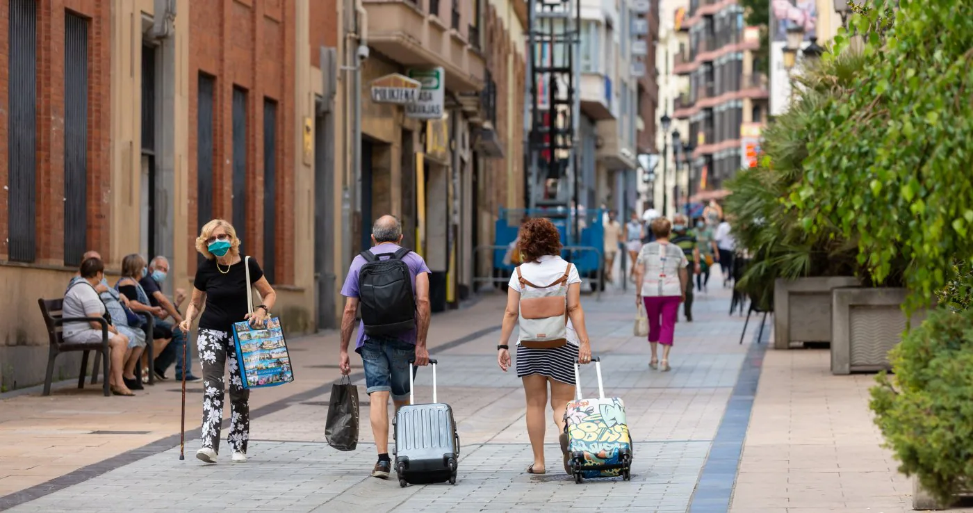 Una pareja de turistas camina por la calle Portales de Logroño portando sus maletas. / SONIA TERCERO